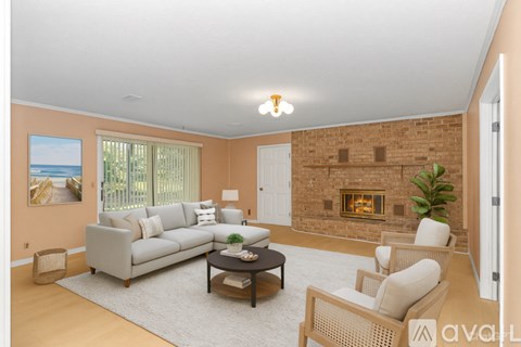 A living room with a grey couch, a coffee table, a fireplace, and a painting of a beach scene on the wall.