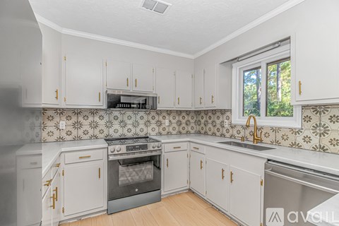 A kitchen with white cabinets and a tiled backsplash.