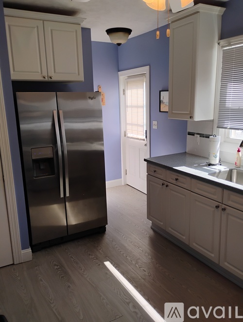 A kitchen with a stainless steel refrigerator and wooden flooring.