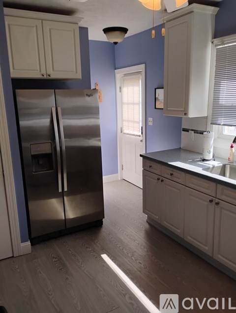 A kitchen with a stainless steel refrigerator and wooden flooring.