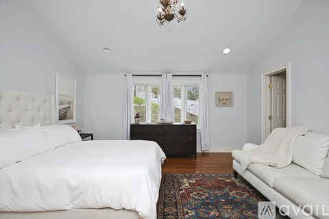 A bedroom with a white bed and a white couch.