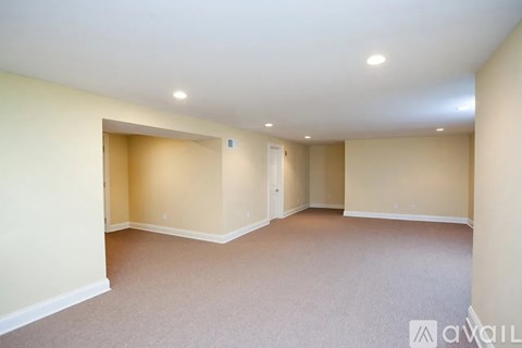 A spacious room with a carpeted floor and white walls.