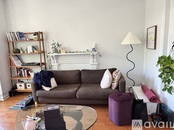 A living room with a grey couch, a glass coffee table, and a bookshelf.