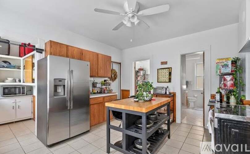 A kitchen with a refrigerator, a table, and a ceiling fan.