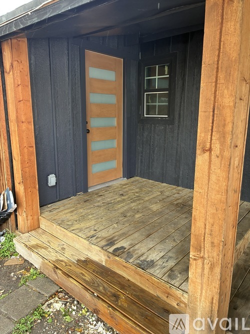 A wooden deck leads to a door with a window on the side.