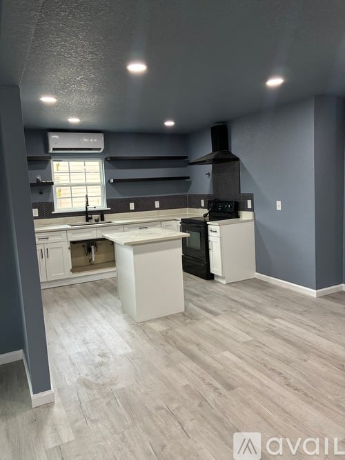 A kitchen with a white island and a black stove top oven.