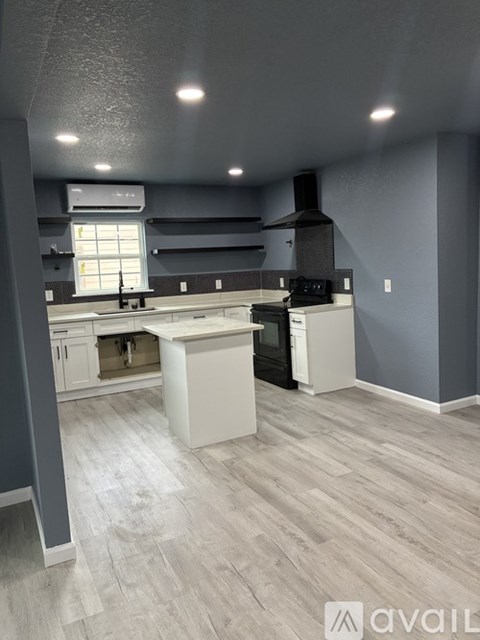 A kitchen with a white island and a black stove top oven.