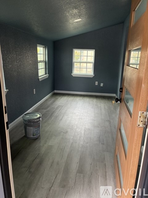 A room with a wooden floor and a door on the right side.