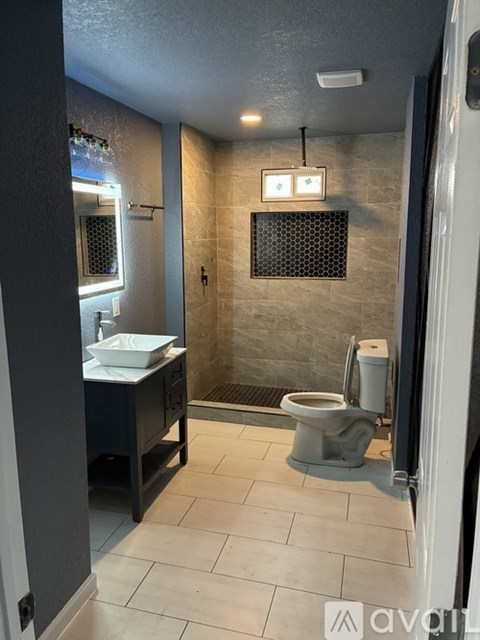 A bathroom with a toilet, sink, and mirror.