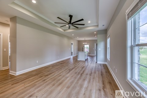 A spacious room with wooden floors and a ceiling fan.