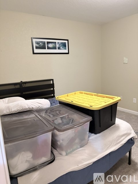 A bed with a black headboard and a yellow plastic container on top of it.