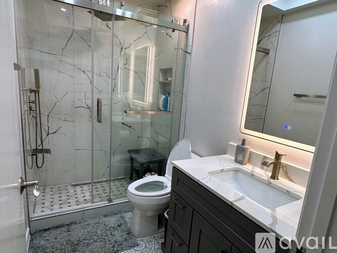 A bathroom with a toilet, sink, and glass shower stall.