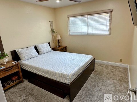 A bedroom with a bed, nightstand, and window.