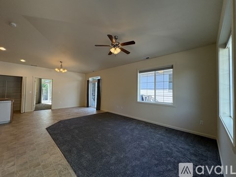 A spacious room with a ceiling fan and large windows.