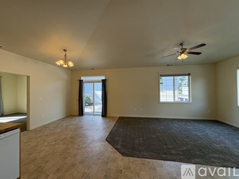 A spacious living room with a rug, ceiling fan, and sliding glass doors.