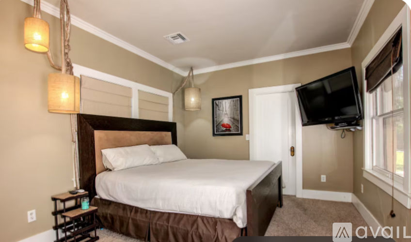 A bedroom with a large bed and a flat screen TV mounted on the wall.