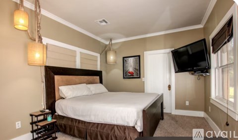 A bedroom with a large bed and a flat screen TV mounted on the wall.