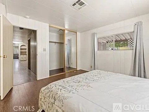 A bedroom with a large bed and a mirrored closet door.