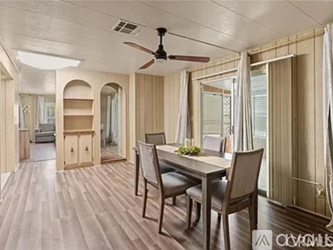 A dining room with a table and chairs and a ceiling fan.