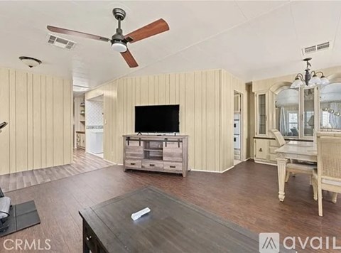 A living room with a television, a coffee table, and a ceiling fan.