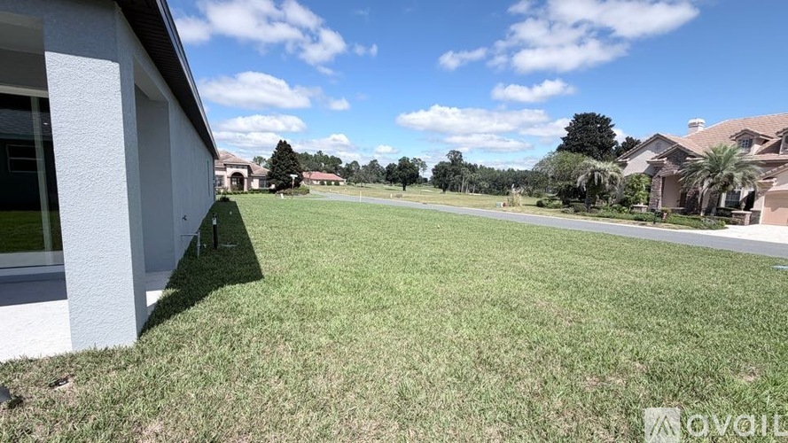 A large grassy area in front of a house with a clear blue sky.