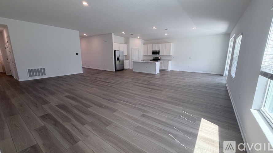 A spacious room with wooden flooring and white walls.