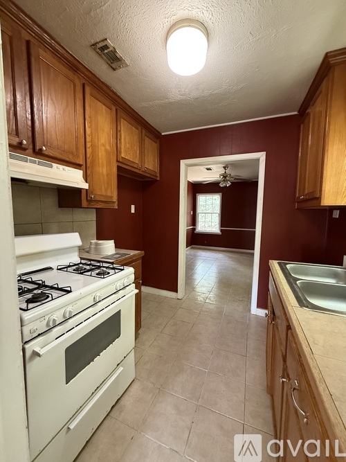 A kitchen with a white gas stove and wooden cabinets.