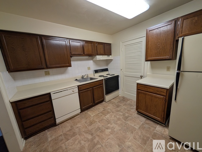 A kitchen with brown cabinets and a white fridge.