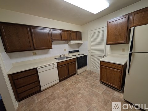 A kitchen with brown cabinets and a white fridge.