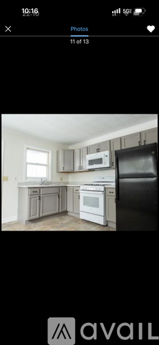 A kitchen with white appliances and a black refrigerator.