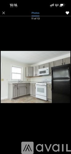 A kitchen with white appliances and a black refrigerator.