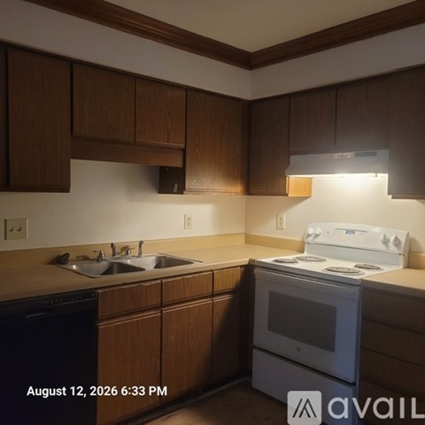 A kitchen with wooden cabinets and a white stove top oven.