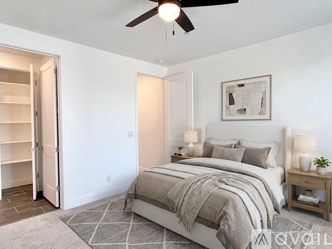 A bedroom with a bed, a ceiling fan, and a nightstand with a lamp.