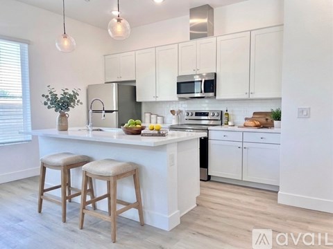 A kitchen with white cabinets and a white island with two stools.