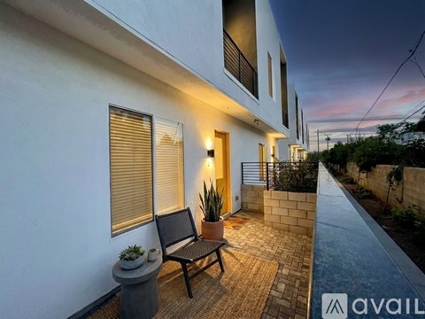 A modern house with a white exterior and a wooden bench on the patio.