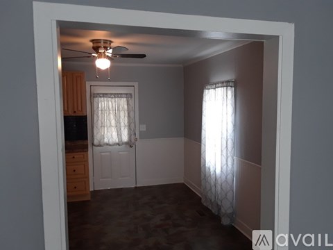 A room with a ceiling fan and a window with curtains.