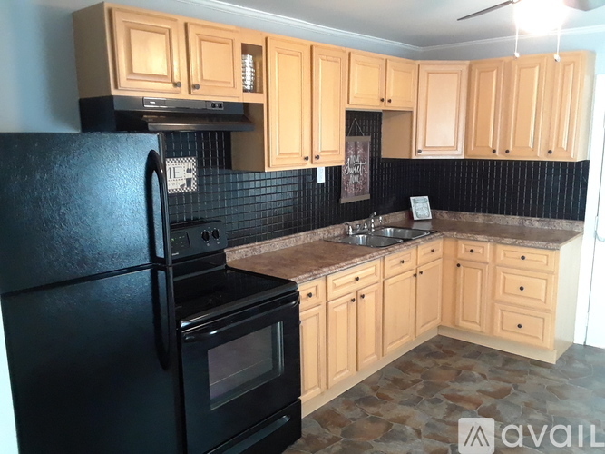 A kitchen with black appliances and wooden cabinets.