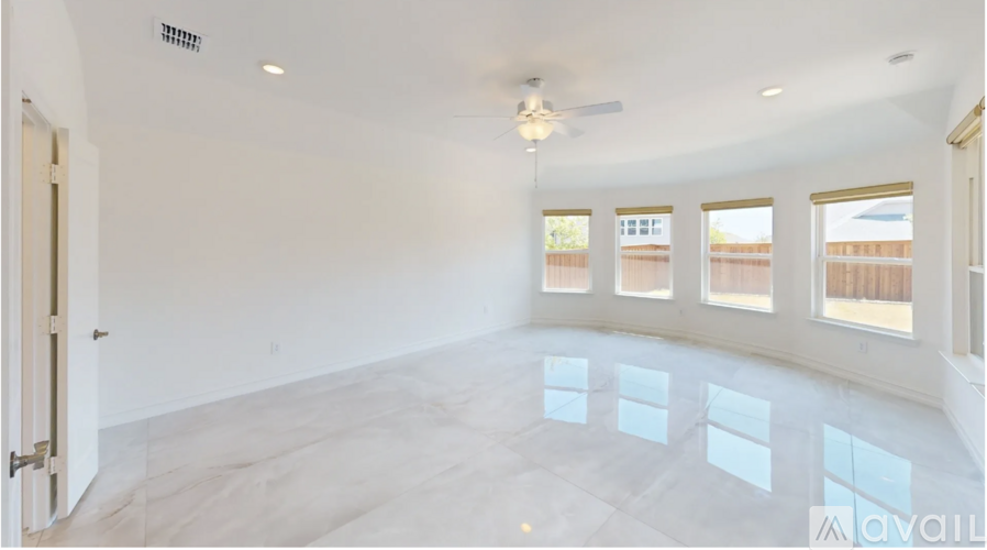 A spacious room with a ceiling fan and large windows.