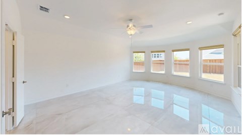 A spacious room with a ceiling fan and large windows.