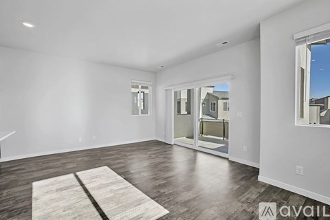 A spacious room with a rug on the floor and a sliding glass door leading outside.