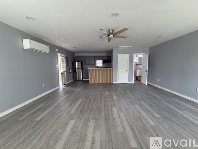 A spacious room with a ceiling fan and wooden flooring.