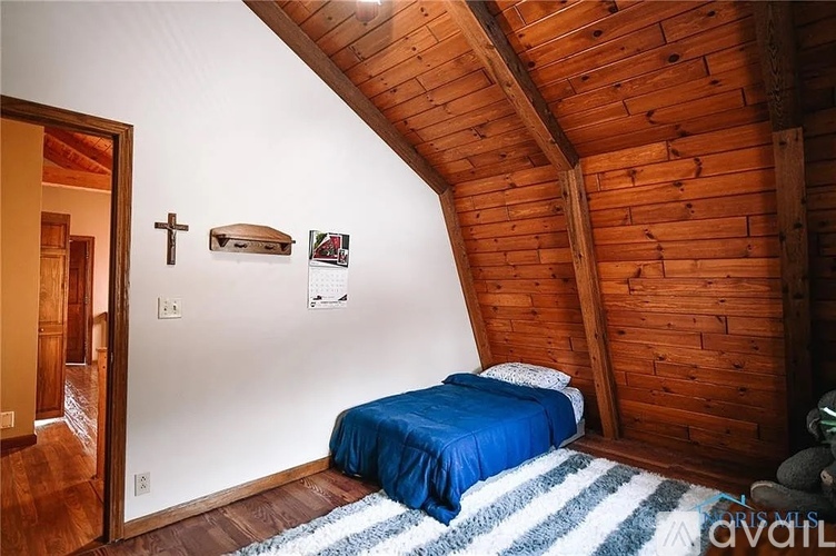 A bedroom with a bed and a cross on the wall.