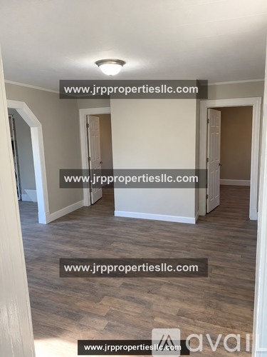 A room with wooden flooring and white walls, with a website address displayed on the wall.
