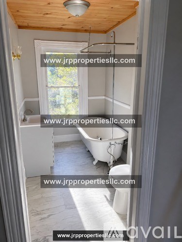 A bathroom with a tub and a toilet.