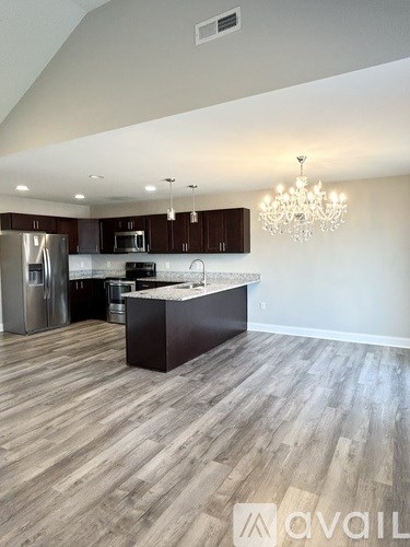 A modern kitchen with wooden floors and a chandelier.