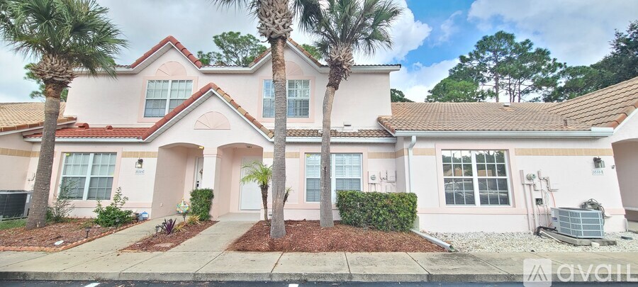 A house with a red roof and a palm tree in front.