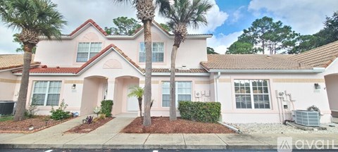 A house with a red roof and a palm tree in front.
