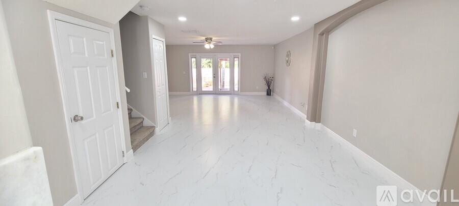 A spacious hallway with white marble flooring and a white door on the left.