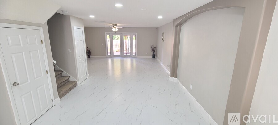 A spacious room with white flooring and a door on the left.