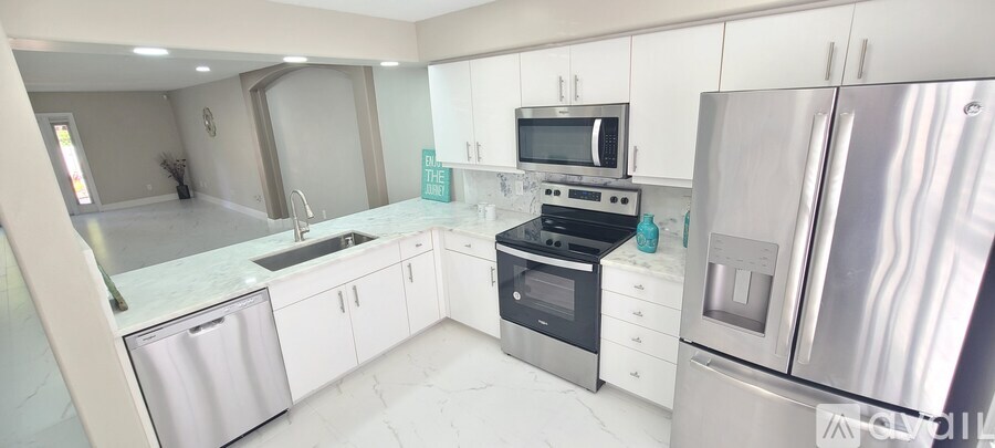 A modern kitchen with white cabinets and stainless steel appliances.